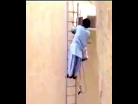 عامل يصلح جهاز تكييف على سلم متأرجح